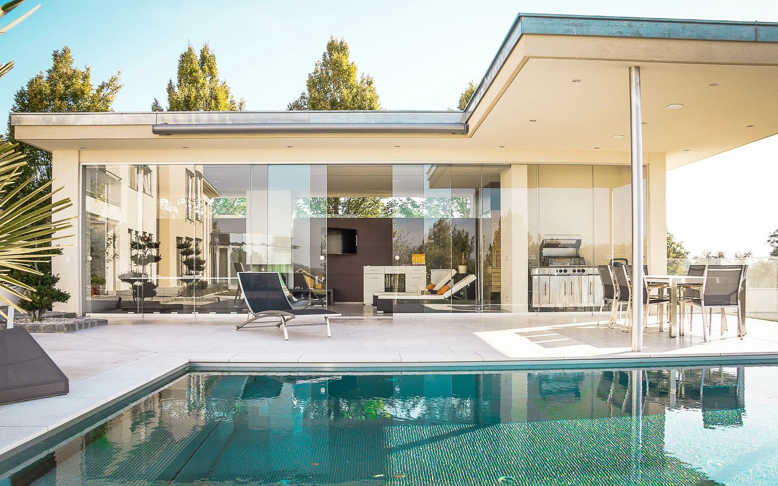 Single-story modern detached structure with glass walls opening to a terrace — representative imagery, not a completed JMB project